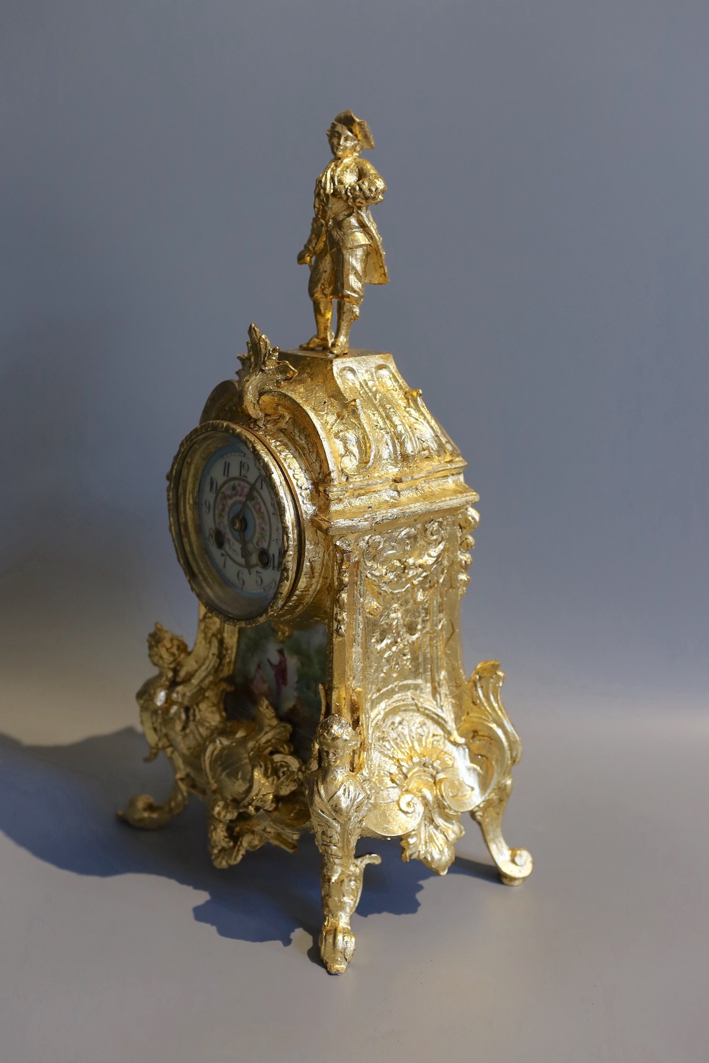 A 19th century French gilt metal and porcelain eight day mantel clock, with figural pediment, height 43cm